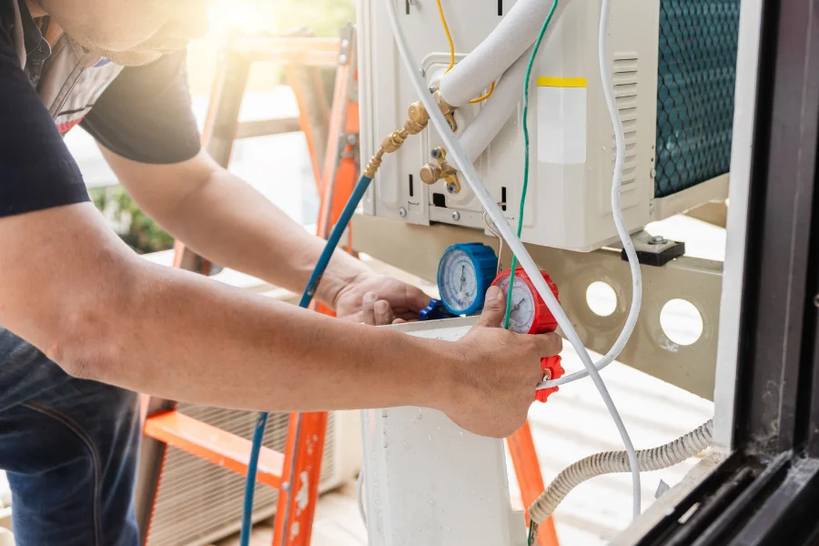 Technician checking refrigerant levels with manifold gauges during an AC tune up in Huntington Beach.