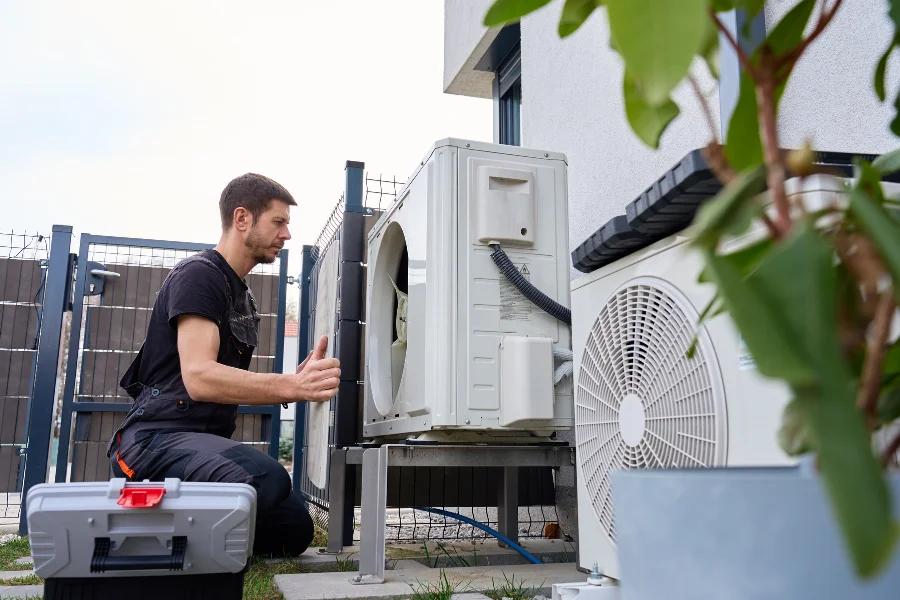 Professional technician kneeling next to a side discharge heat pump unit during an installation in Temecula.