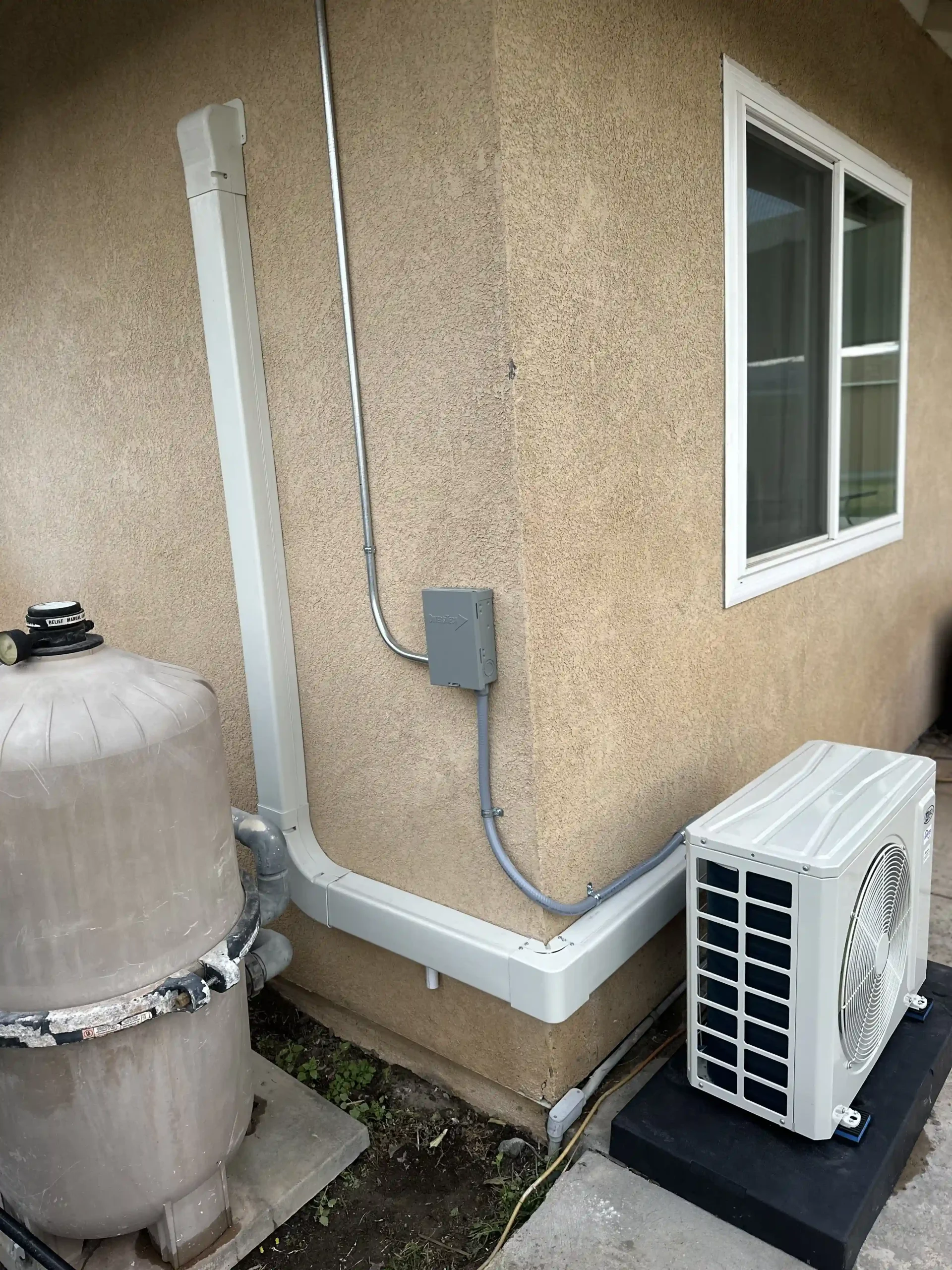 A newly installed outdoor mini split air conditioning unit on a concrete pad next to a stucco house wall in Irvine.