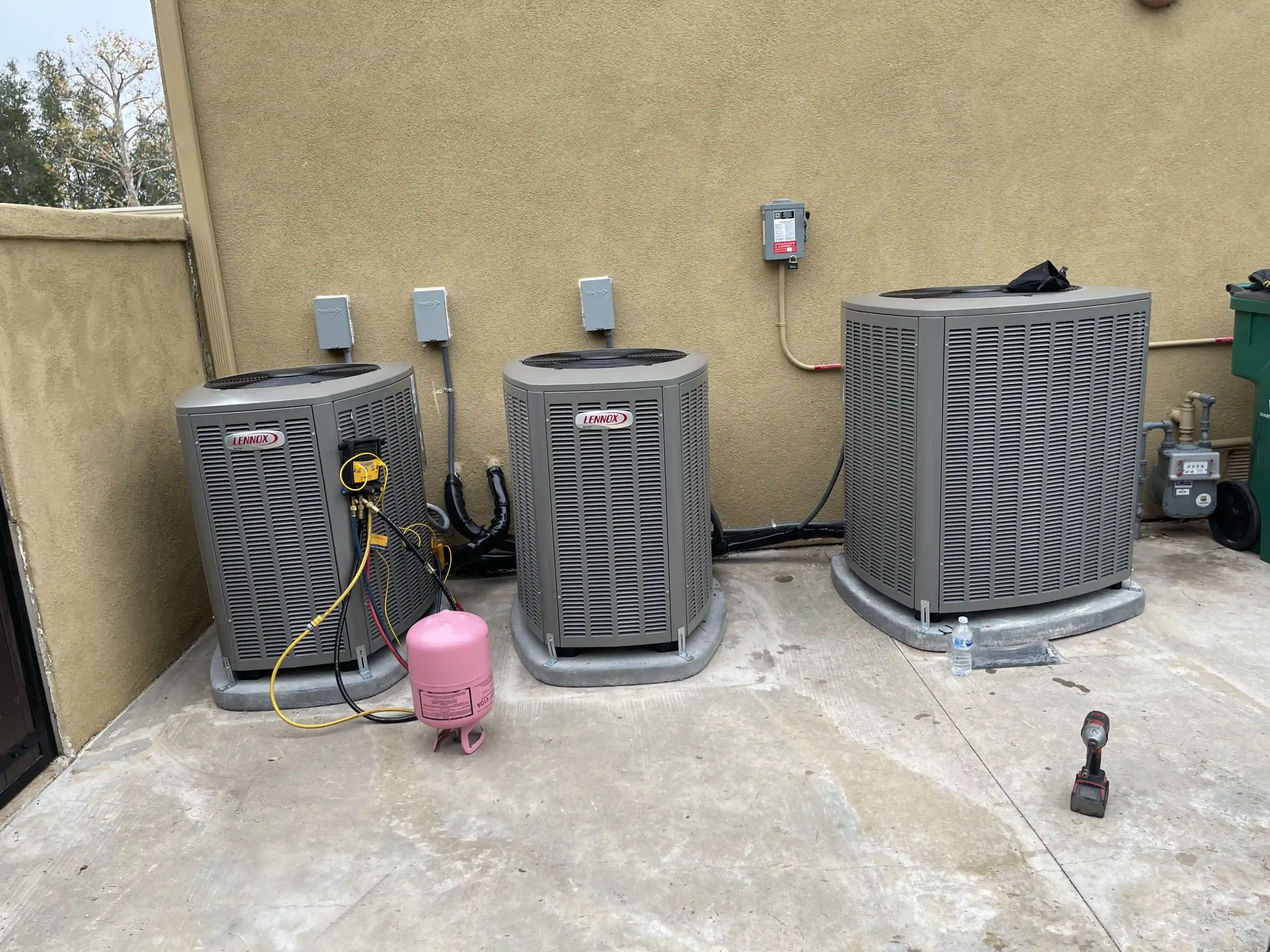 Technician tools and refrigerant tank next to three outdoor Lennox air conditioners in San Bernardino.