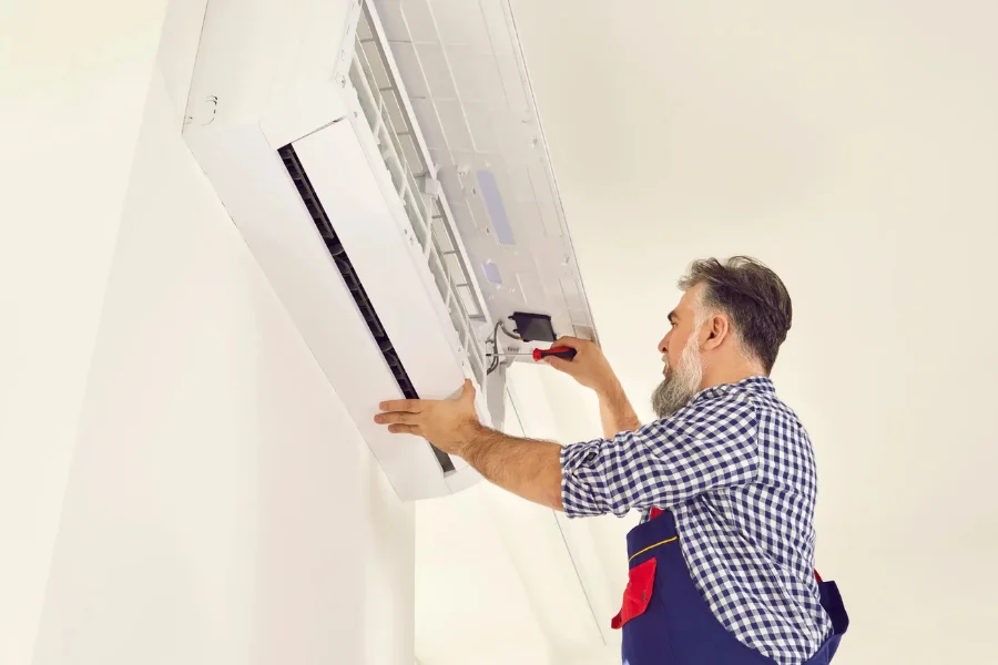 Professional service technician fixing a white wall mounted mini split air conditioner in Newport Beach.