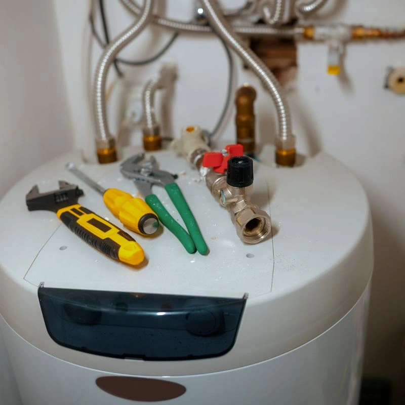 A selection of professional hand tools and a brass plumbing valve resting on top of a white appliance unit.