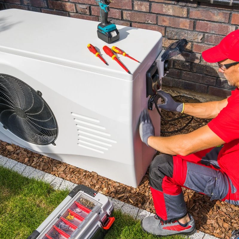 An HVAC installer securing electrical conduit paths on a white outdoor unit cabinet during a thermal comfort upgrade.